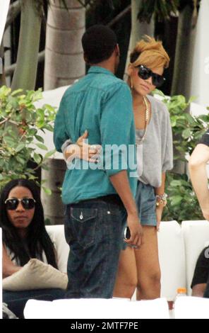 Rihanna gets a hug during a relaxing afternoon by the pool at the Fontainebleau Miami Beach. The songstress, who drank rose wine, chatted and laughed with friends in a private cabana for a couple of hours. Rihanna wore an all grey outfit including a tshirt, a pair of shorts and high heeled shoes and accessorized with large hooped earrings and a gold necklace. Miami, FL. 2/5/10. Stock Photo