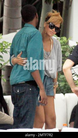 Rihanna gets a hug during a relaxing afternoon by the pool at the Fontainebleau Miami Beach. The songstress, who drank rose wine, chatted and laughed with friends in a private cabana for a couple of hours. Rihanna wore an all grey outfit including a tshirt, a pair of shorts and high heeled shoes and accessorized with large hooped earrings and a gold necklace. Miami, FL. 2/5/10. Stock Photo