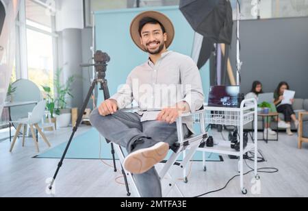 Portrait, happy and photographer in studio for photo shoot, relax and confident in professional setup. Face, asian male and magazine photography Stock Photo