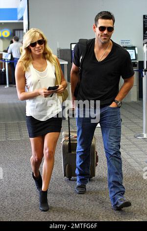 Despite recent reports of a cheating scandal, LeAnn Rimes and Eddie Cibrian look very happy together as they share a kiss in the check-in line after arriving to catch a flight at Burbank Airport for their flight. The two strolled together, smiling, and ever chivalrous, Eddie made sure to unhook a chain allowing LeAnn easier access to the security checkpoint. Los Angeles, CA. 8/9/10. Stock Photo