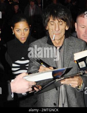 Sucking back on a cigarette and wearing white high-top sneakers The Rolling Stones guitarist Ronnie Wood and girlfriend, Brazilian polo coach Ana Araujo, are flanked by security guards as they arrive at the West End's Ambassadors Theatre for an intimate one-night only concert launching the tribute album Boogie 4 Stu.  The album was created by Ben Waters in memory of the late Ian Stewart (aka Stu), co-founder of The Rolling Stones, who died from a heart attack at the age of 47 in 1985.  Proceeds from the album will go to the British Heart Foundation.  As Ronnie made his way about the outside of Stock Photo