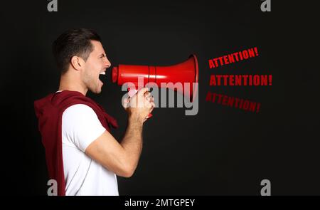 Handsome man with megaphone on black background Stock Photo
