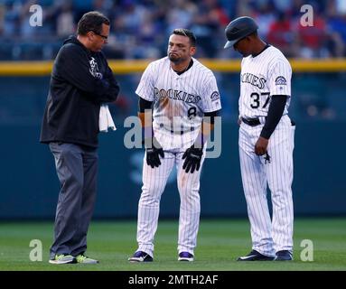 Colorado Rockies' Charlie Blackmon, left, shows to trainer Scott Gehret  where a foul ball hit his batting helmet as he stood in the on-deck circle,  during the third inning of the team's