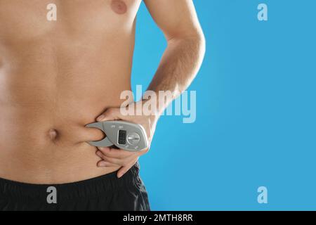 https://l450v.alamy.com/450v/2mth8rr/man-measuring-body-fat-layer-with-digital-caliper-on-light-blue-background-space-for-text-nutritionists-tool-2mth8rr.jpg