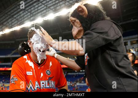 Wearing a monkey mask, Miami Marlins' Miguel Rojas, top, prepares to hit  J.T. Realmuto with a shaving cream pie as Realmuto does a postgame  interview after a baseball game against the Atlanta