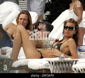 Tattooed Beauty Queen, Sarah Gerth, wife of German footballer Jermaine Jones, relaxes poolside at her luxury hotel in a star string bikini. The blonde beauty also got a cuddle from one of her twins and lounged with her own animal print designer Dolce & Gabbana pillows. Miami Beach, FL. 12/29/10. Stock Photo