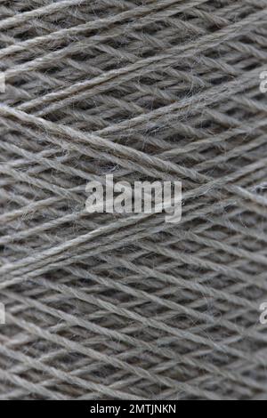 Macro texture of a light gray thread that is wound onball shape resulting in an abstract background of straight lines that intersect Stock Photo