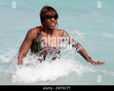 Serena Williams spends a relaxing afternoon on the beach soaking up the sun wearing a brightly colored cutaway bathing suit. She took a ride on a jetski, sipped a cocktail and chatted with pals. She also splashed around in the ocean which was a bit chilly at first and she screamed as the cold waves hit her. Serena is currently on a tennis break due to injury. Miami, FL. 3/25/10.      . Stock Photo