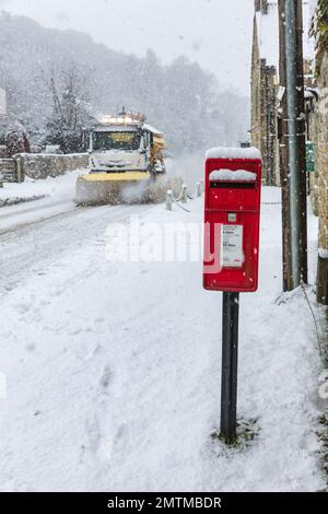 A gritter wagon and red telephone box in deep snow at Hutton Le Hole, The North Yorkshire Moors, UK Stock Photo