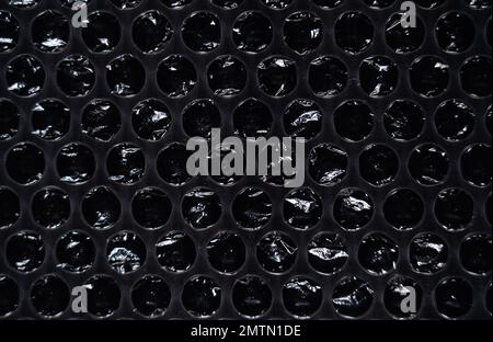 Bubble wrap texture on black background. The film protects the surface from impacts. polyethylene. Stock Photo