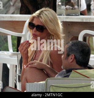 EXCLUSIVE!! Swedish model Victoria Silvstedt stuns in a pastel dress that shows off her famous curves during an afternoon by the pool. The 38 year old bombshell blonde sipped wine as she chatted with friends, re-applied her lip gloss, then sat in the sun at the end of the day soaking up the last few rays before leaving her hotel. Miami Beach, FL. 13th October 2012. Stock Photo