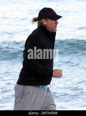 EXCLUSIVE!! Val Kilmer jogs off his Thanksgiving dinner with a sunset run on the beach. What a difference a few months makes! The actor who turns 52 on new years eve, was looking slimmer than when he was spotted on the set of his film 'Seven Below' in Cincinatti last August and at one point appeared to be loosing his shorts. Kilmer has several upcoming filming projects including 'The Hard Ride,' a western movie about a legendary gunfighter. Miami Beach, FL. 29th November 2011. Stock Photo