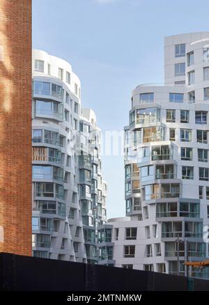 Red brickwork juxtaposed to white rippled facade of Prospect Place. Prospect Place Battersea Power Station Frank Gehry, London, United Kingdom. Archit Stock Photo
