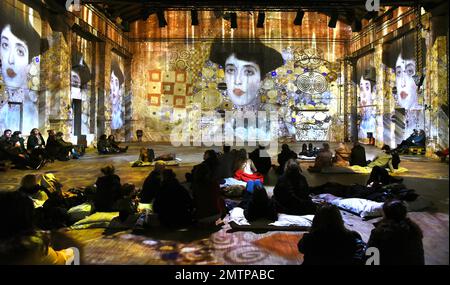 29 January 2023, Saxony, Leipzig: In the Kunstkraftwerk, a former combined heat and power plant, visitors watch the multimedia installation 'Gustav Klimt - GoldExperience,' in which the famous portrait of Adele Bloch-Bauer is also projected on the walls. In the show by the Italian Stefano Fake and his Fake Factory, the stations and works of the Austrian artist Gustav Klimt (1862-1918), one of the most important representatives of Viennese Art Nouveau, are shown in various thematic areas as a monumental projection throughout the room and on the floor. The show will be on view until May 28, 2023 Stock Photo