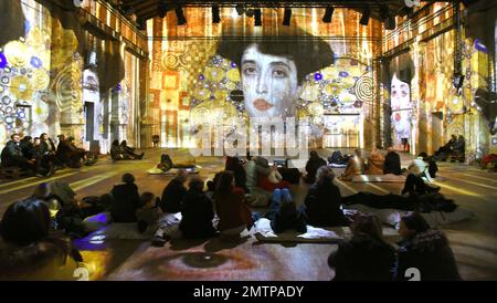 29 January 2023, Saxony, Leipzig: In the Kunstkraftwerk, a former combined heat and power plant, visitors watch the multimedia installation 'Gustav Klimt - GoldExperience,' in which the famous portrait of Adele Bloch-Bauer is also projected on the walls. In the show by the Italian Stefano Fake and his Fake Factory, the stations and works of the Austrian artist Gustav Klimt (1862-1918), one of the most important representatives of Viennese Art Nouveau, are shown in various thematic areas as a monumental projection throughout the room and on the floor. The show will be on view until May 28, 2023 Stock Photo