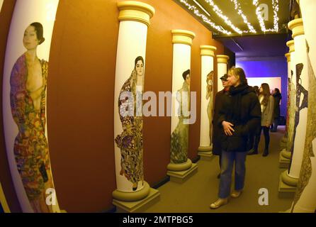 29 January 2023, Saxony, Leipzig: In the Kunstkraftwerk, a former combined heat and power plant, visitors walk along a colonnade of famous portraits of women by Gustav Klimt in the exhibition 'Gustav Klimt - GoldExperience'. The room is part of the show of the Italian Stefano Fake and his Fake Factory, where in different thematic areas the stations of the Austrian artist Gustav iKlimt (1862-1918), one of the most important representatives of the Viennese Art Nouveau can be seen. Asss monumental projection, the most famous portraits and landscapes can be seen in the multisensory exhibition unti Stock Photo