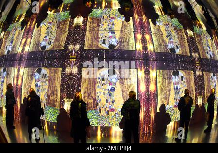 29 January 2023, Saxony, Leipzig: In the Kunstkraftwerk, a former combined heat and power plant, visitors stand in a hall of mirrors, in which the famous painting 'Kiss' is also reflected several times. The mirrored room is part of the multimedia installation 'Gustav Klimt - GoldExperience', in which many famous paintings are projected in the room. In the show by Italian Stefano Fake and his Fake Factory, the stations of Austrian artist Gustav Klimt (1862-1918), who is one of the most important representatives of Viennese Art Nouveau, are shown in different thematic areas as a monumental proje Stock Photo