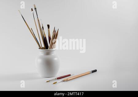 watercolor artists brushes and sketching pencils in a vase isolated on a white background Stock Photo