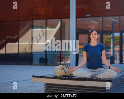 Cheerful asian female student standing outdoors, happy young eastern woman walking in campus Vienna University of Economics, break after class, rest a Stock Photo