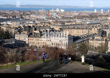 Edinburgh, Scotland, UK. 1st February 2023.  People out and about on a cold, sunny but windy Calton Hill. View northwards over city rooftops to Granton and Leith with the Forth estuary and Fife beyond. Credit: Craig Brown/Alamy Live News Stock Photo