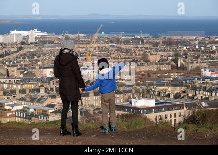 Edinburgh, Scotland, UK. 1st February 2023.  People out and about on a cold, sunny but windy Calton Hill. View northwards over city rooftops to Granton and Leith with the Forth estuary and Fife beyond. Credit: Craig Brown/Alamy Live News Stock Photo