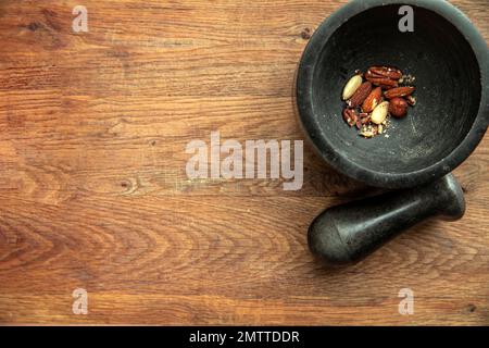 Top angle view of various nuts in stone mortar on a wooden shelf background, almonds, hazelnuts, walnuts dried top view and copy space Stock Photo
