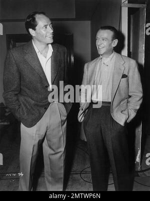 Mel Ferrer visits Fred Astaire on the set of 'Funny Face' in which Astaire woos Audrey Hepburn, who in real life is wed to Ferrer. Stock Photo