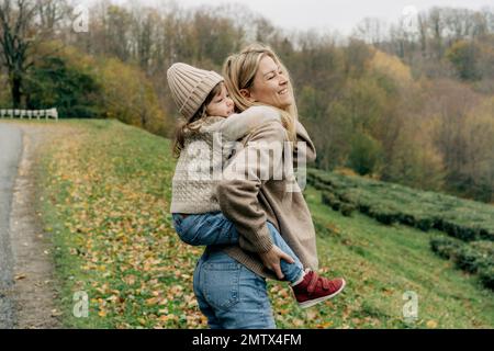 Little Girl Riding On Her Mother's Back Stock Photo