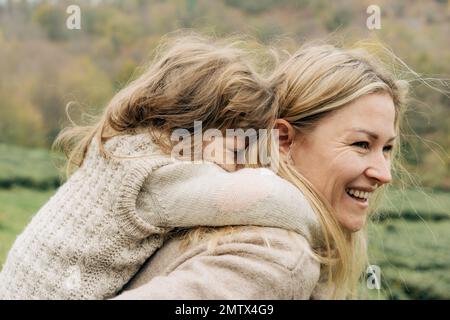 Little Girl Riding On Her Mother's Back Stock Photo