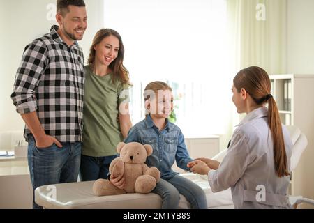 Pediatrician visiting parents and child in hospital bed ward, doctor ...