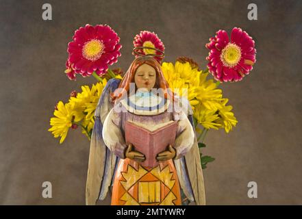 A flower angel serenades a boquet of gerbera daisies on Christmas Sunday. Stock Photo