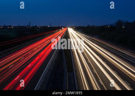 Light trails left by speeding traffic travelling through the night on the M40 motorway in the UK. Slow shutter speed and long exposure photography. Stock Photo