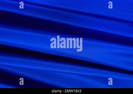 The texture of a luxurious smooth fabric in blue with folds and waves. Blue fabric, material Stock Photo