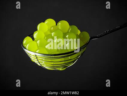 green jelly balls for making bubble tea in a strainer on black background Stock Photo