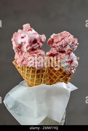 strawberry ice cream in waffle cones on grey background Stock Photo