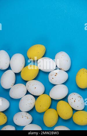 White and yellow chocolate quail eggs on a blue background with room for text. Easter Vertical Banner Stock Photo