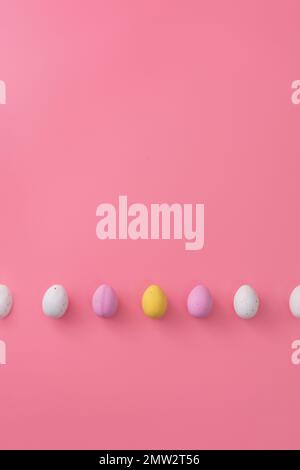 Easter greeting card with sweet colorful little eggs lying in line on pale pink background. Festive sweets. Copy space for text. Lying flat. Stock Photo