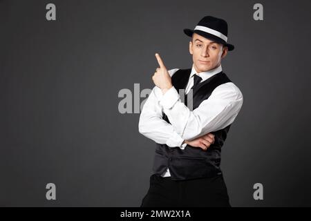 Confident young man posing in gangster style suite. Studio isolated on gray background. Stock Photo