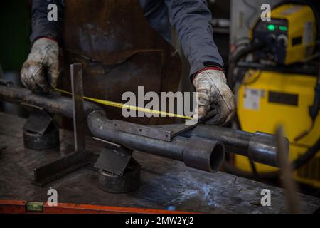 Close-up of a worker's hands measuring a pipe in a factory Stock Photo