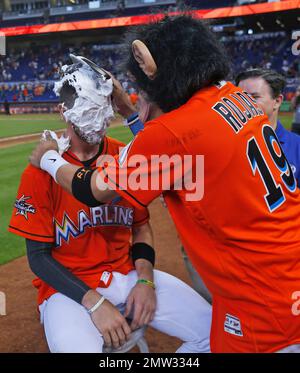 Wearing a monkey mask, Miami Marlins' Miguel Rojas, top, prepares to hit  J.T. Realmuto with a shaving cream pie as Realmuto does a postgame  interview after a baseball game against the Atlanta