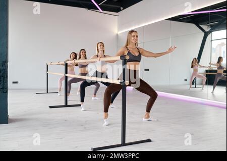 Young smiling female group doing stretching at pilates studio Stock Photo