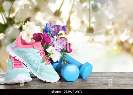 Composition with spring flowers and sports items on wooden table against blurred background Stock Photo