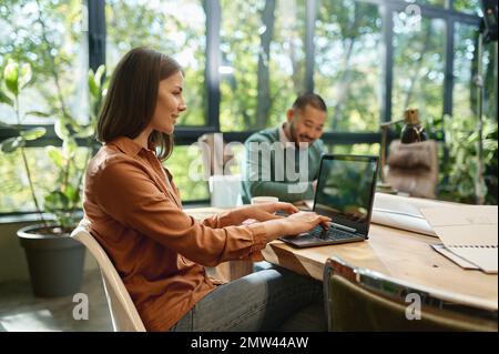 Smiling professional young businesswoman using laptop in coworking space Stock Photo