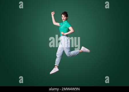 Full body profile side photo of young woman jumping with shocked face expression isolated over green background Stock Photo