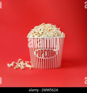 Delicious popcorn in paper bucket on red background Stock Photo