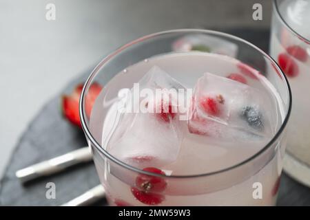 Glass of refreshing drink with ice cubes and berries on table, closeup Stock Photo
