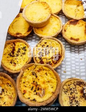 Top view of freshly baked golden quiches placed in the food counter. Stock Photo