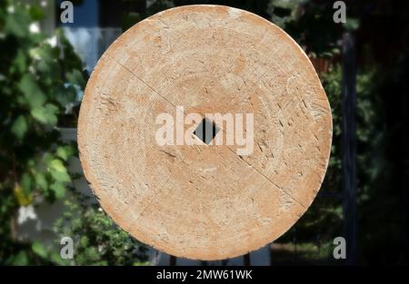 Old grinding stone wheel made of sandstone in close-up Stock Photo