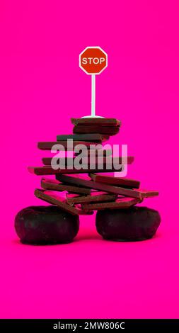 Chocolate and donuts isolated on pink background with stop sign on top Stock Photo