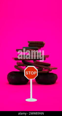 Chocolate and donuts isolated on pink background with stop sign Stock Photo